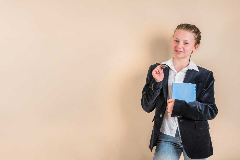 Młoda studentka trzyma legitymację studencką oraz niebieski notatnik